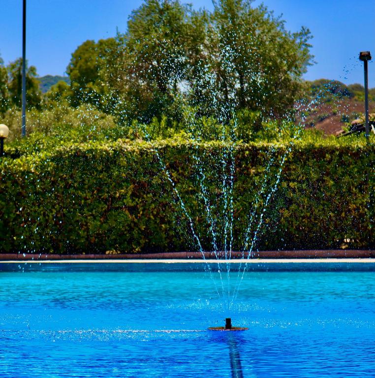 a person in the water in front of a fountain at Villa Aurelia - Pool, BBQ & Tennis Court - San Teodoro in San Teodoro