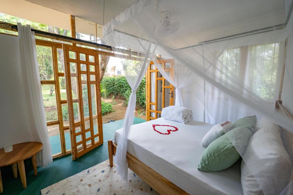 1 dormitorio con 1 cama en una habitación con ventanas en Mkoani Homestay, en Moshi