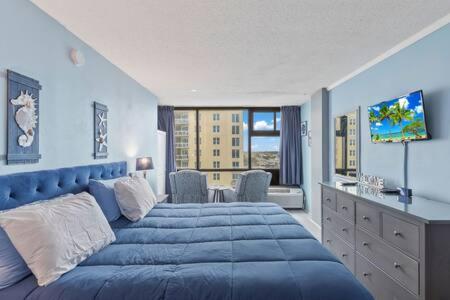 a bedroom with a large blue bed with a television at NEW Oceanside Inn 603 King Bed Ocean Views in Daytona Beach