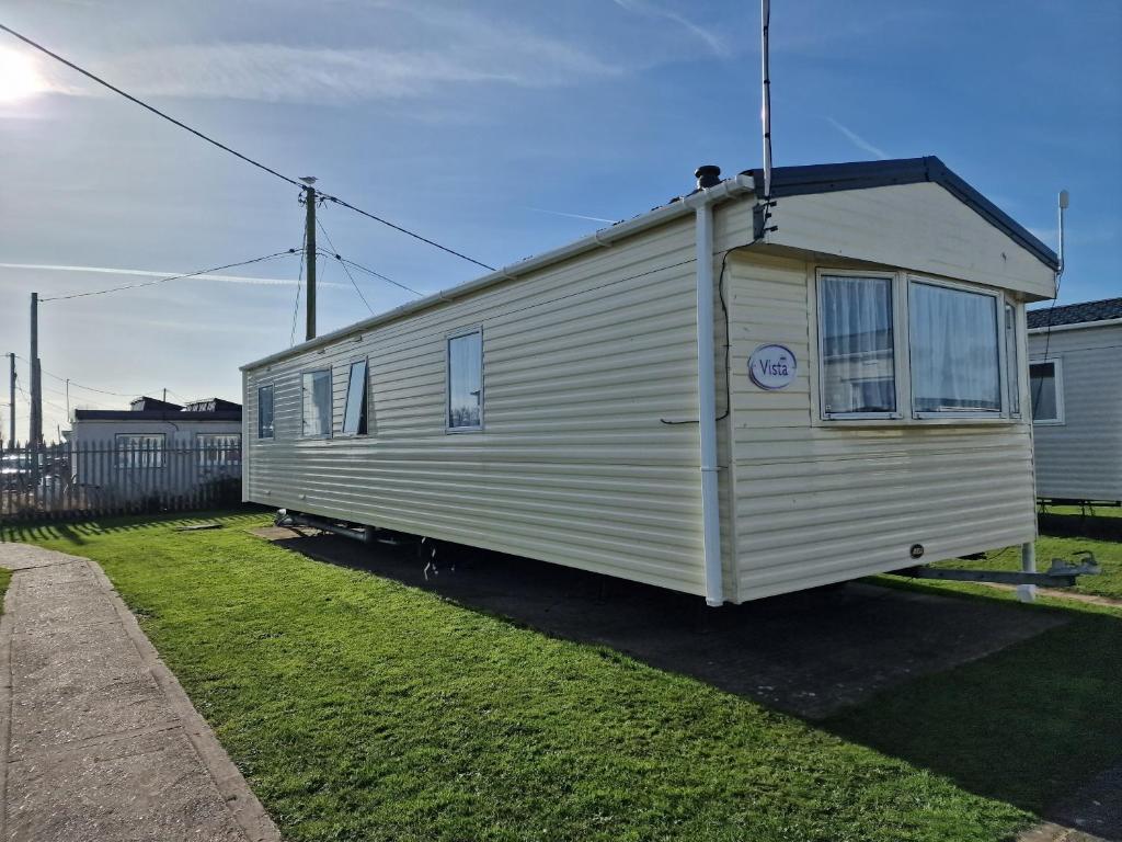 a small white trailer parked in a yard at Lunaeva Holiday Home in Saint Osyth