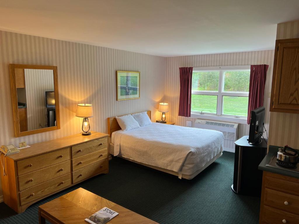 a hotel room with a bed and a mirror at Stowe Motel & Snowdrift in Stowe