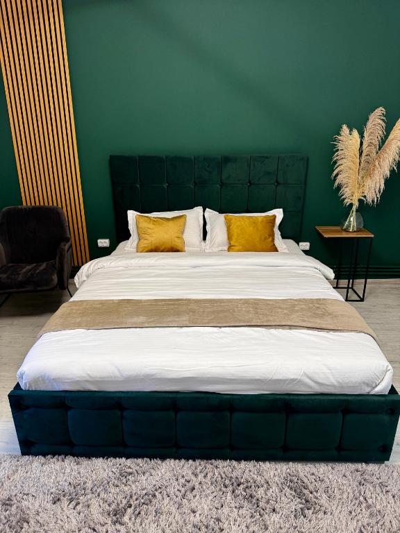 a large bed with yellow pillows in a green room at Garsoniera moderna One bedroom in Turnu Măgurele