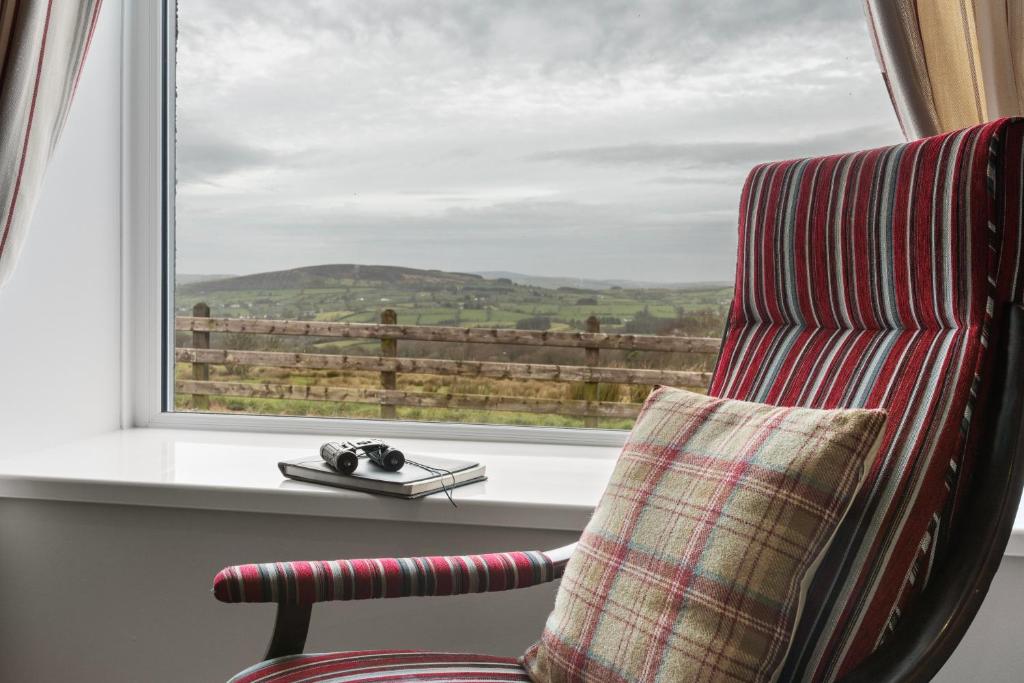 a chair sitting next to a window with a view at Sperrin Mountain Escape in Derry Londonderry