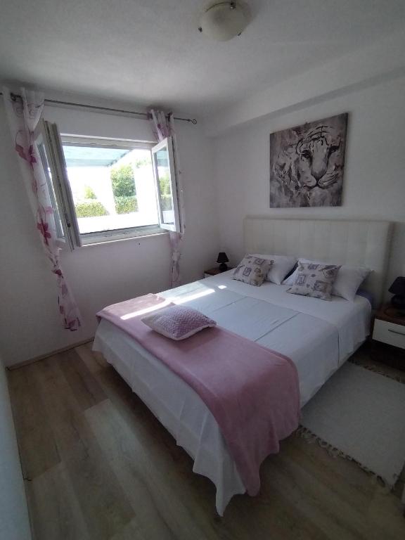 a bedroom with a large white bed and a window at Apartmani Kulin 2 in Kaštela