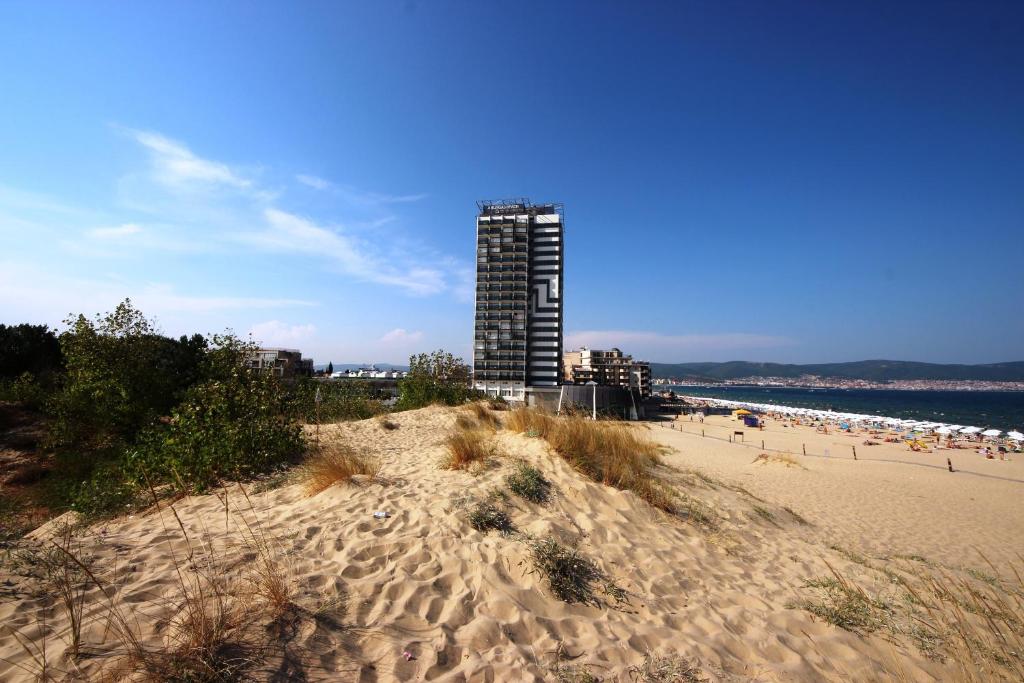 Una vista de una playa con un edificio al fondo. en Menada Dune Residence Apartments, en Sunny Beach