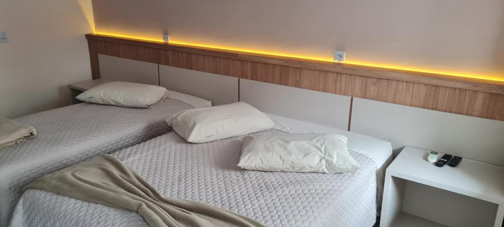 2 camas con sábanas blancas y almohadas en una habitación en Hotel em Timbo Grande, 