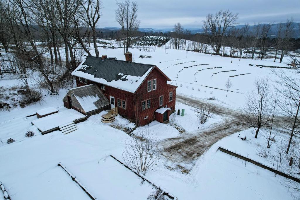 an old red house in a snow covered field at Experience the Rocks Estate like never before with a stay at the Gardeners Cottage! in Bethlehem