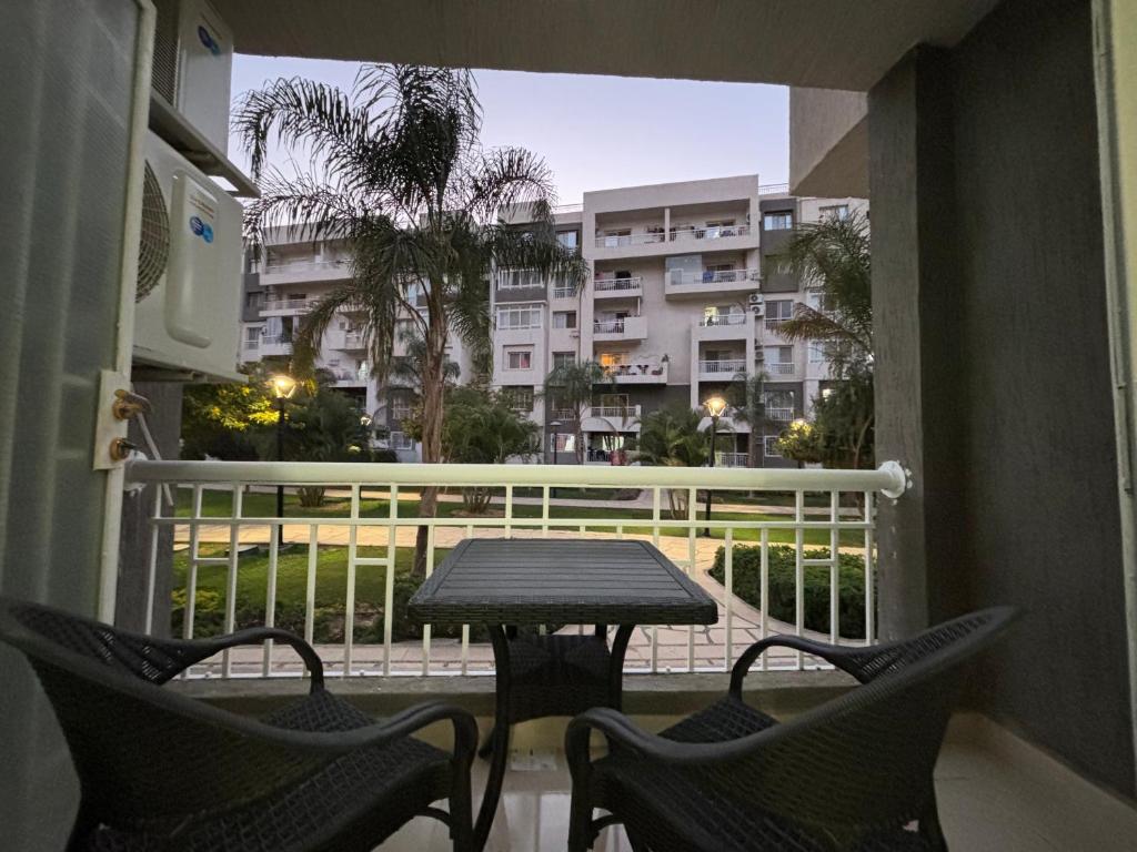 einen Tisch und Stühle auf einem Balkon mit Blick auf ein Gebäude in der Unterkunft Luxury Inn:2BR Amazing Garden View in Madinaty B10 in Madinaty