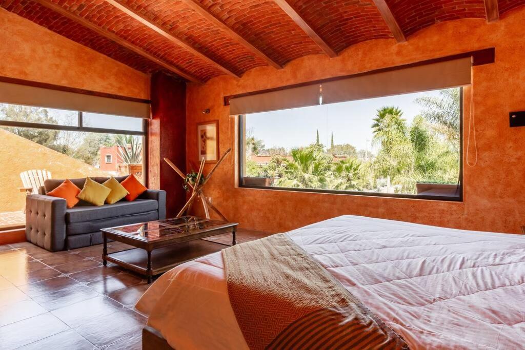 a bedroom with a bed and a couch and a large window at Hermosa Casa 20p/6Hab/Pool/Jacuzzi Tequisquiapan in La Laja