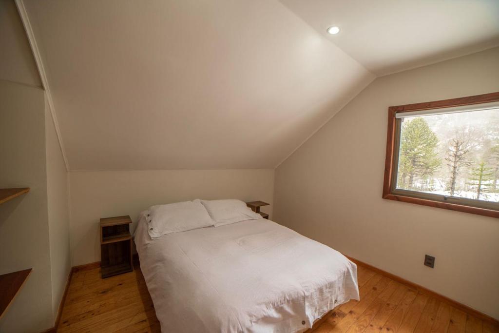 een slaapkamer met een wit bed en een raam bij Cabañas Sierra Nevada in Malalcahuello
