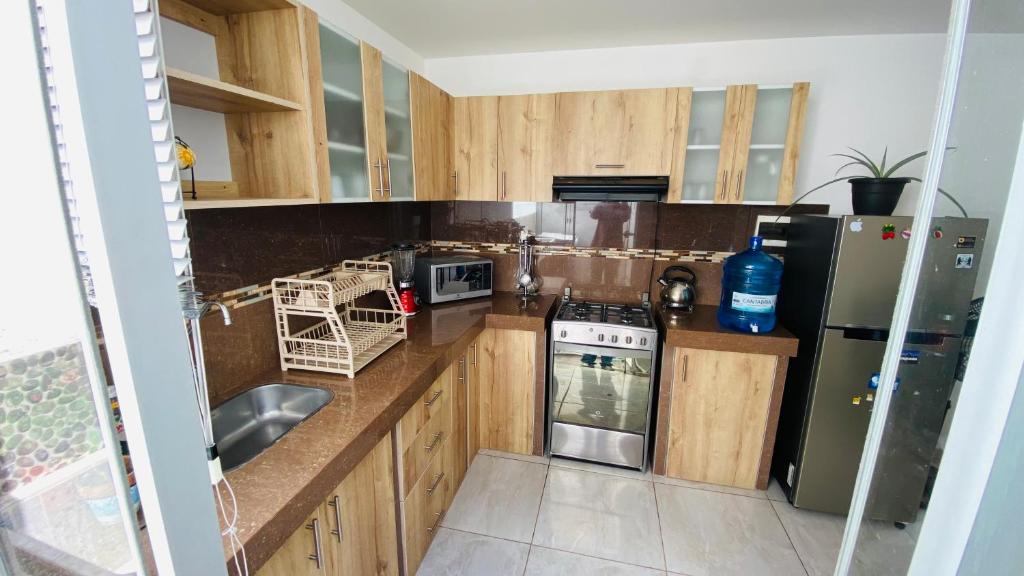une cuisine avec des placards en bois et des appareils en acier inoxydable dans l'établissement Apartamento/Departamento independiente nuevo, à Tacna