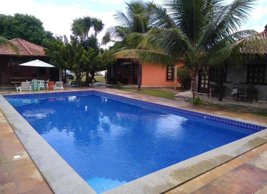 une grande piscine bleue à côté d'une maison dans l'établissement Bangalô Amarelo, à Prado