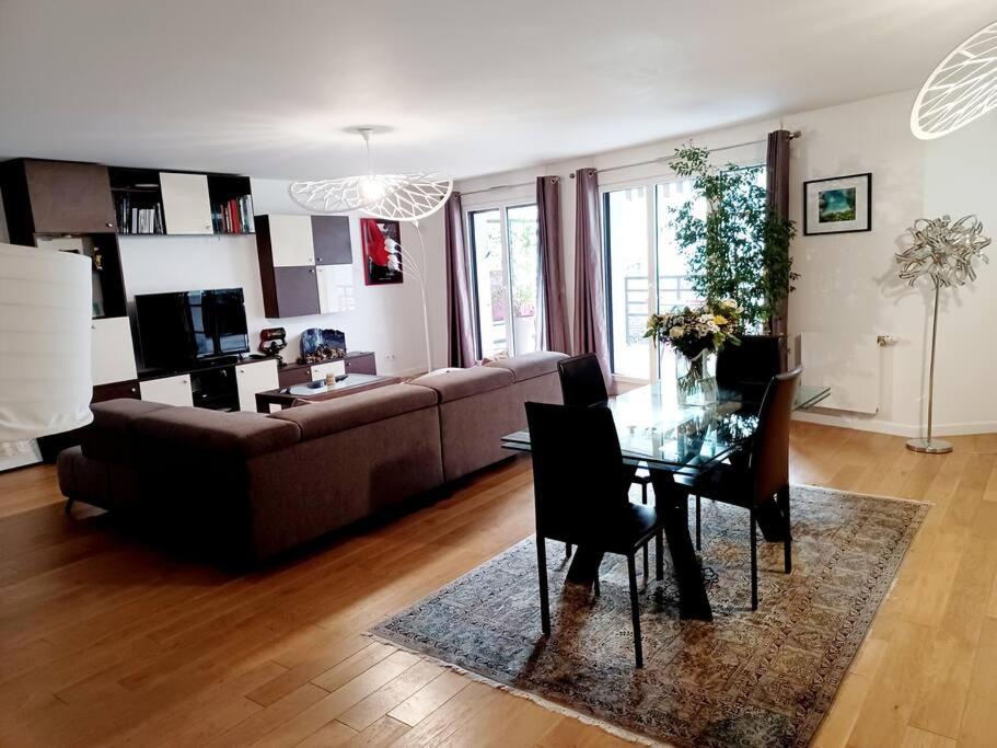 ein Wohnzimmer mit einem Sofa und einem Glastisch in der Unterkunft Magnifique Appartement à 500 mètres du Métro in Levallois-Perret