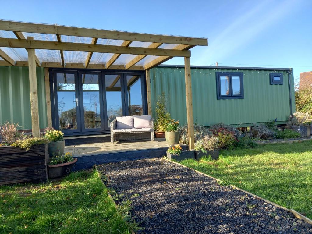 a green tiny house with a pergola at Sweet Pea Cabin in Badsey