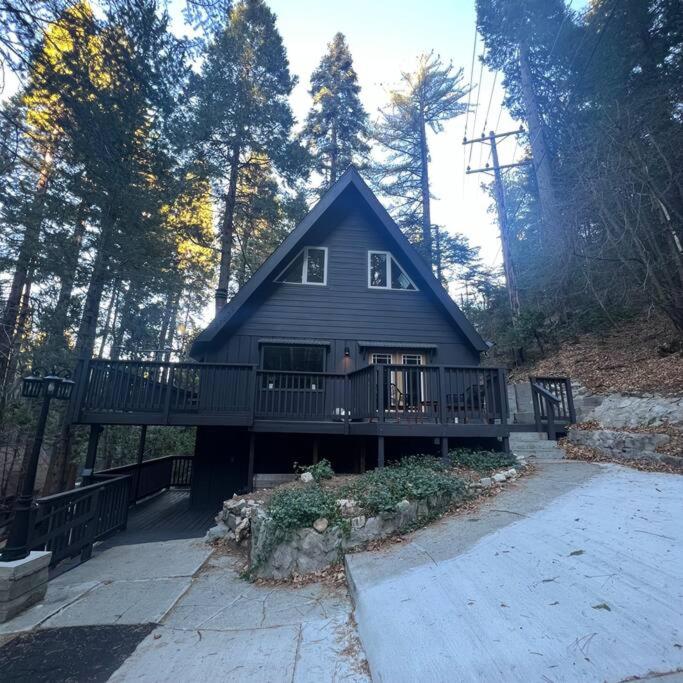 a large house with a deck in the woods at Lake Arrowhead Lux Black Cabin in Lake Arrowhead