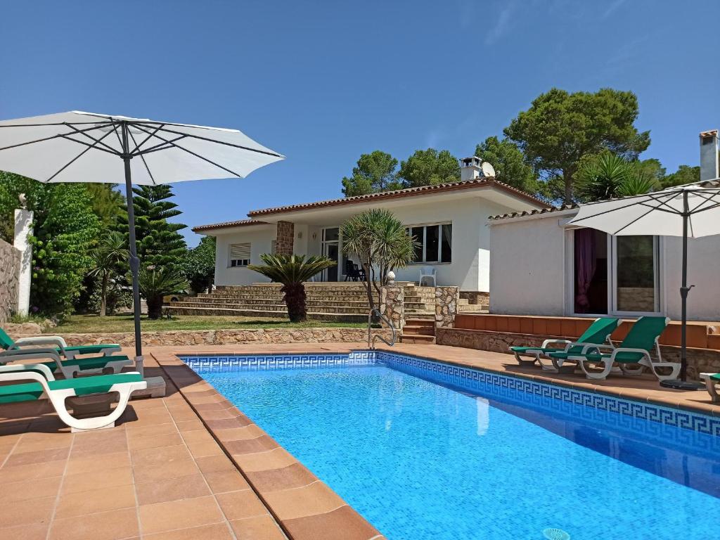 una piscina con sillas y sombrillas junto a una casa en Casa L'Escala, 4 dormitorios, 8 personas - ES-89-127, en Torroella de Montgrí