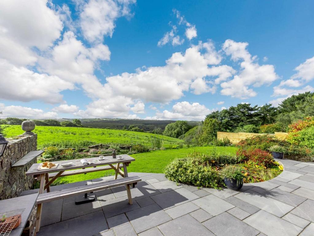 um pátio com uma mesa e vista para um campo em 5 Bed in Widemouth Bay 89900 em Week Saint Mary