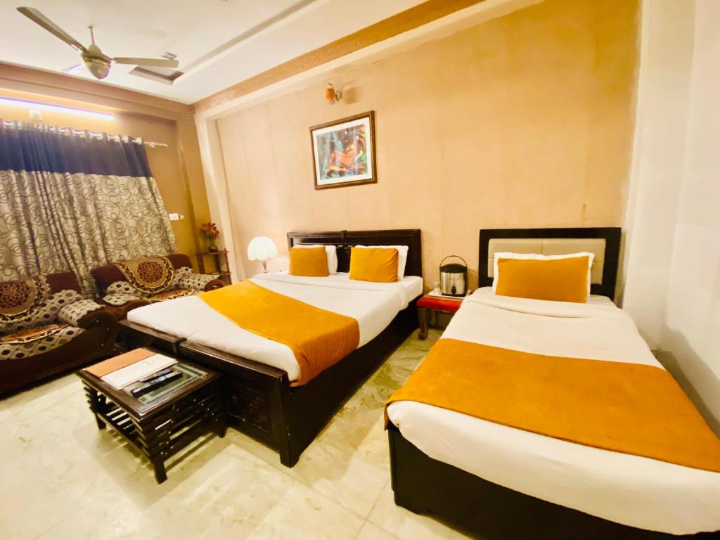 a hotel room with two beds and a couch at Hotel Meenakshi Udaipur - Family Preffered Hotel in Udaipur