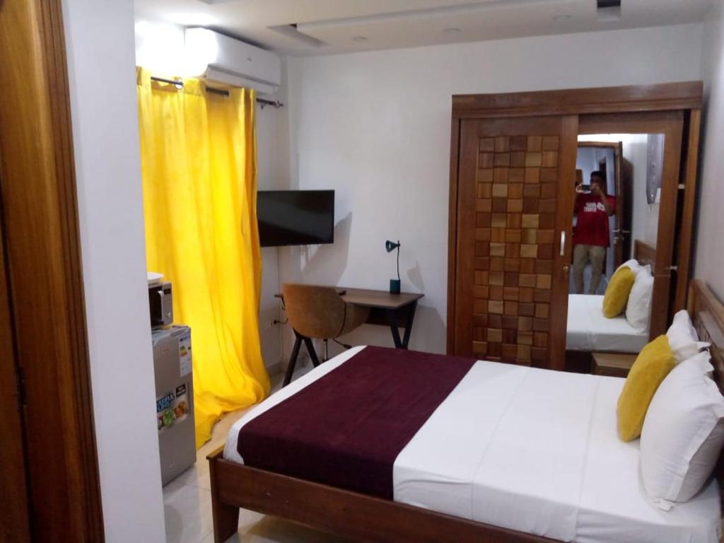 a bedroom with a bed and a desk with a yellow curtain at RESIDENCE FABY 1 in Dakar