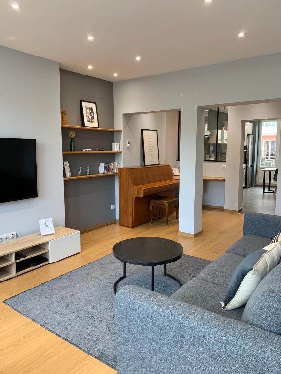 un salon avec un canapé bleu et une télévision dans l'établissement Appartement Lumineux Hypercentre, à Épinal