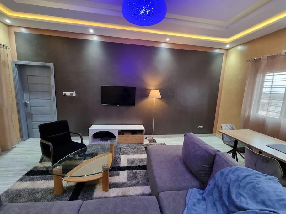 ein Wohnzimmer mit einem Sofa und einem TV in der Unterkunft Résidence Schilo - appartement équipé avec piscine privée et rooftop in Abomey-Calavi