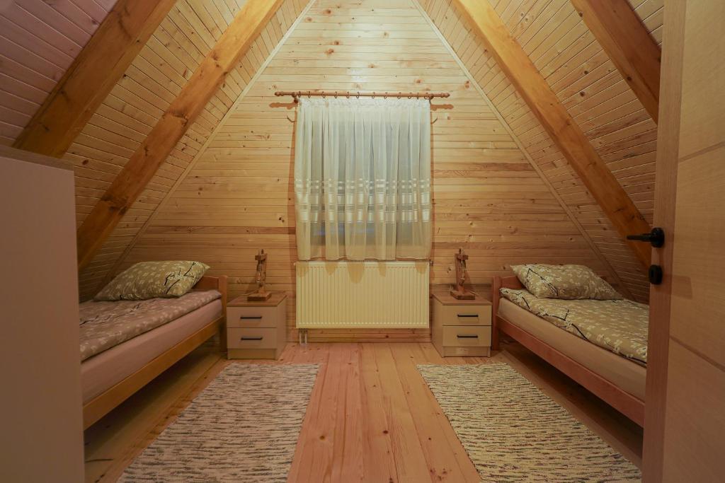 a attic room with two beds and a window at Vila Marija HP in Han Pijesak