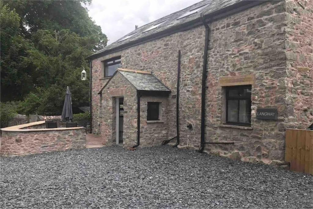 a stone house with a courtyard in front of it at Langway in Gatebeck