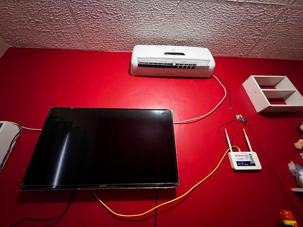 uma televisão e um aquecedor numa parede vermelha em Residência Shalom em Presidente Figueiredo