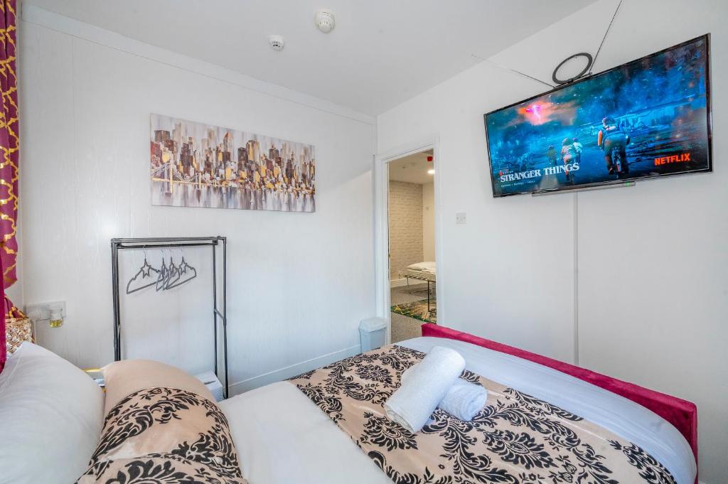 um quarto com uma cama e uma televisão na parede em *RA9GH* For your most relaxed & Cosy stay + Free Parking + Free Fast WiFi * em Bramley