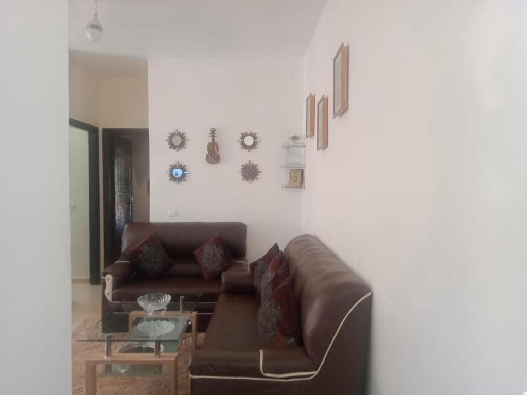 a living room with a brown couch and a table at Appartement du luxe in Ifrane