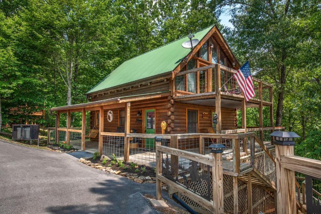 une cabane en rondins avec un toit vert et un drapeau américain dans l'établissement Hook, Line and Sinker Cabin features firepit and hot tub!, à Sevierville