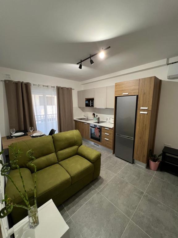 a living room with a green couch and a kitchen at A brand new apartment in Pieta