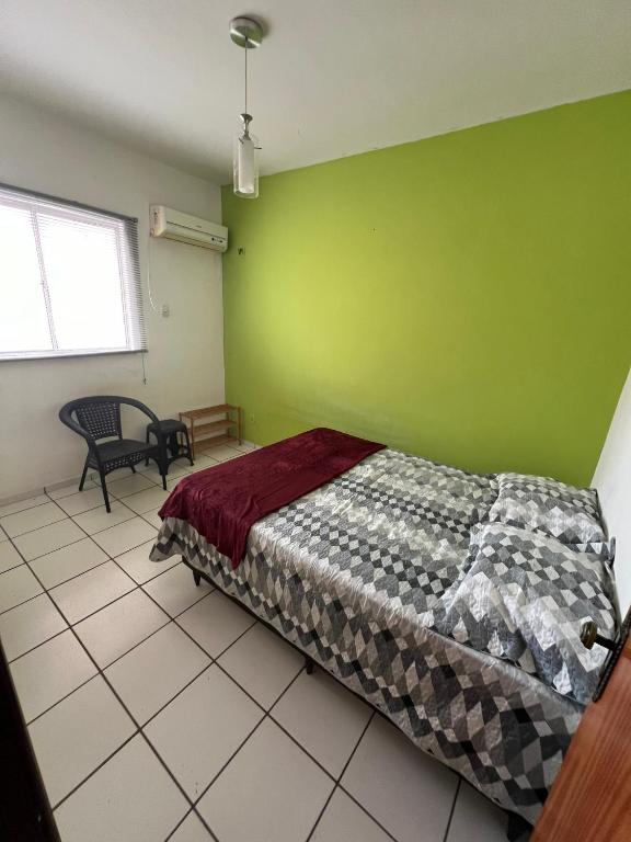 a bedroom with a bed and a green wall at Quarto acolhedor em apto com ótima localização. in São Luís