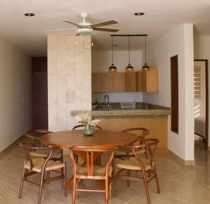 a dining room table with chairs and a kitchen at Departamento mar y arena in Chicxulub
