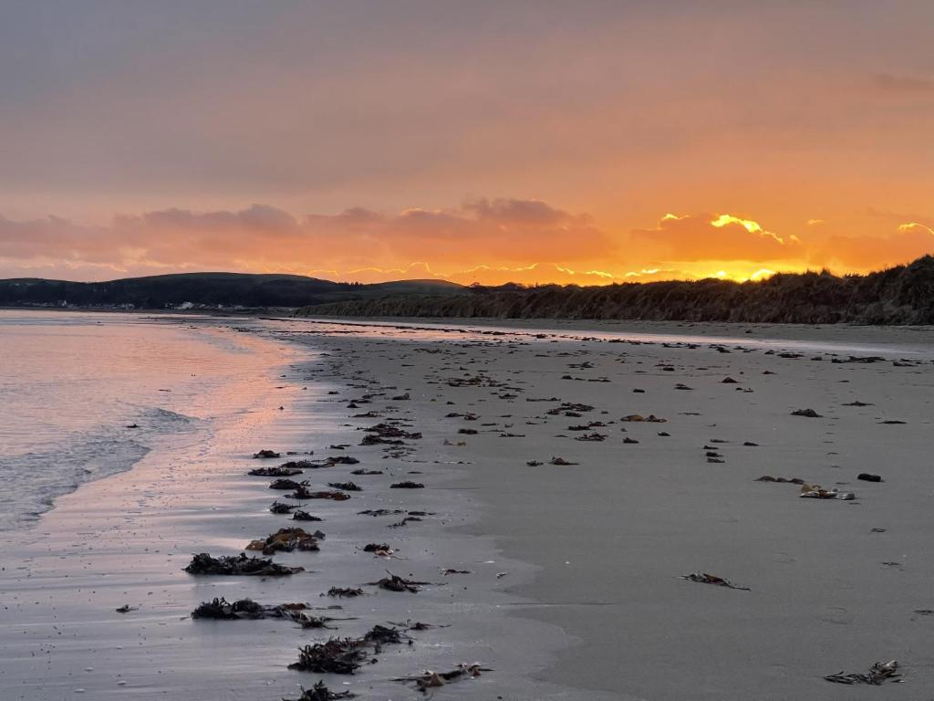 a beach with the sun setting in the distance at Tigh Na Mara Hotel in Sandhead