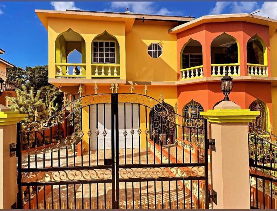 uma casa amarela e laranja com um portão preto em The Manor Deluxe Suite em Ocho Rios