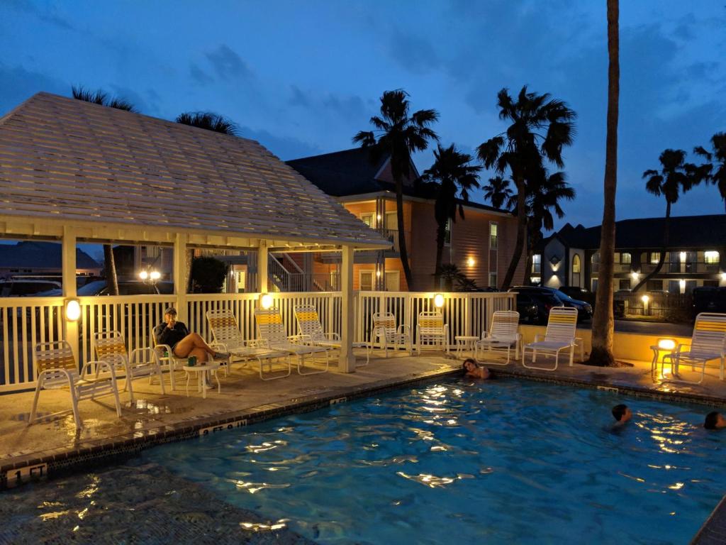 a person sitting on chairs in a pool at night at Seashell Village Resort near the beach with kitchens in Port Aransas