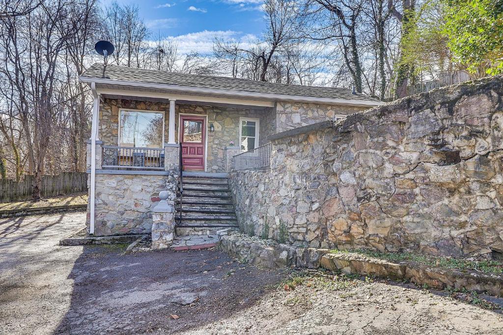 a stone house with a red door and a stone wall at Eclectic Stone Cottage, Walk to Downtown Staunton! in Staunton