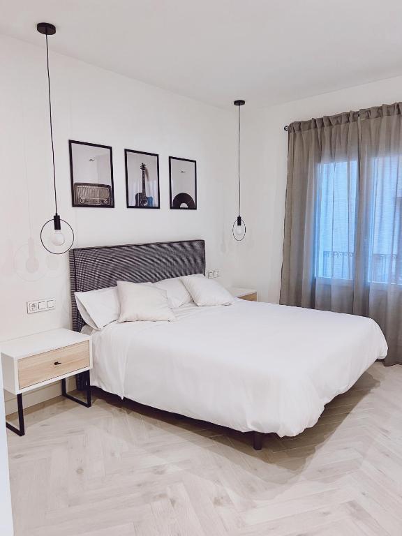 a white bedroom with a large white bed and a window at Apartamento Domus in Teruel