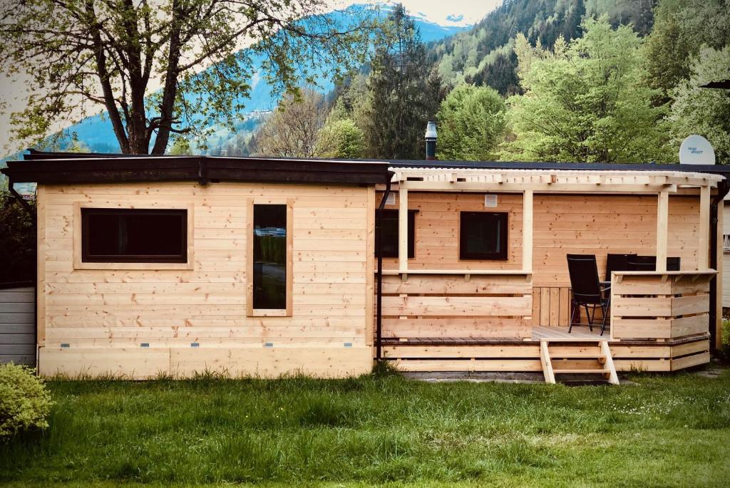 duża drewniana kabina z gankiem w trawie w obiekcie Mountainview Lodge - Chalet im Zillertal direkt am 5 Sterne Campingplatz Aufenfeld mit Hallenbad und Sauna w mieście Aschau