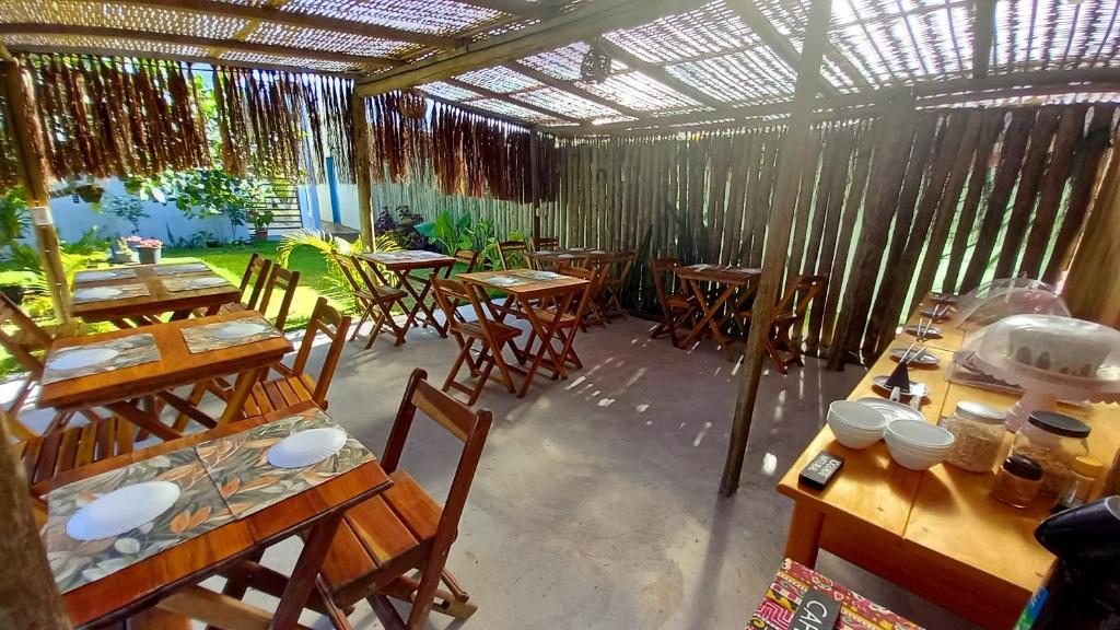 a restaurant with wooden tables and chairs and a ceiling at Pousada Kiarô Caraíva in Caraíva