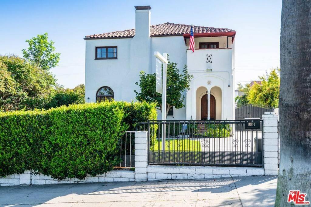 uma casa branca com um portão e arbustos em The Manhattan Villa em Los Angeles