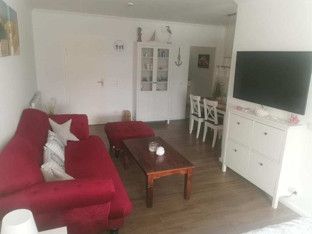 uma sala de estar com um sofá vermelho e uma mesa em Ferienwohnung Küstenkind em Wendtorf