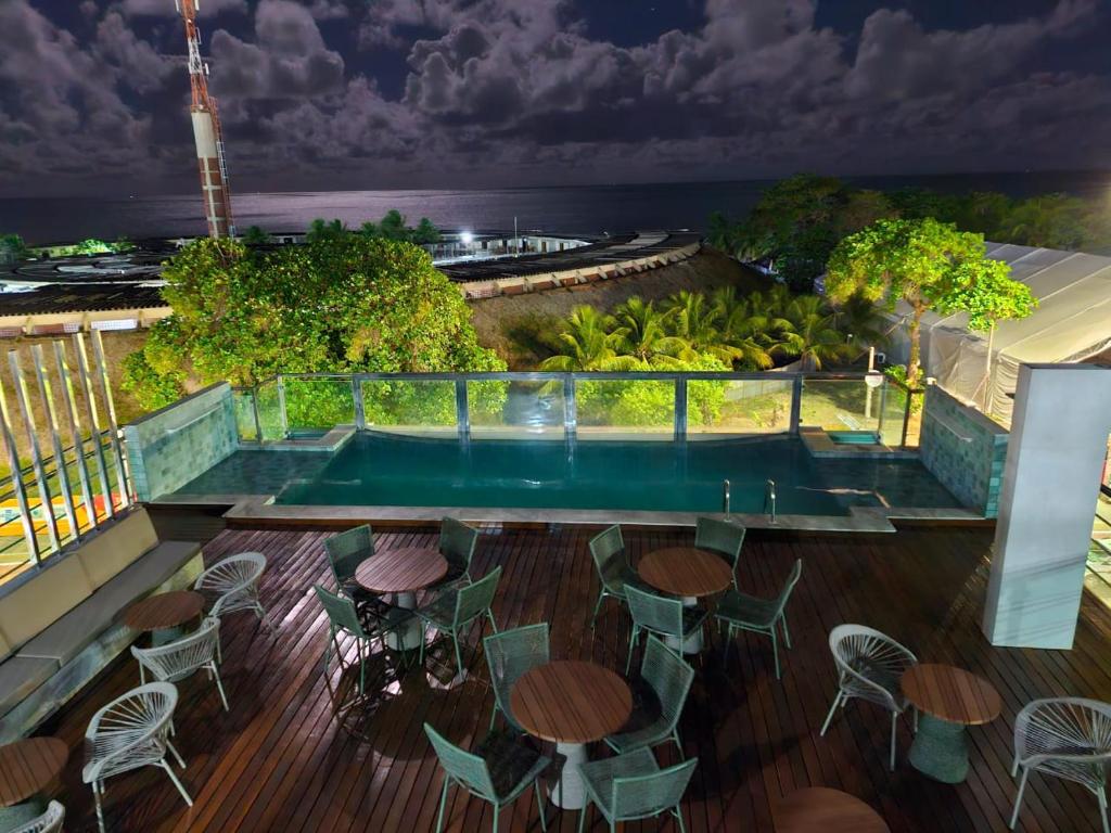 un balcón con mesas y sillas y una piscina en Israel Flat da Mar & Sol, en João Pessoa