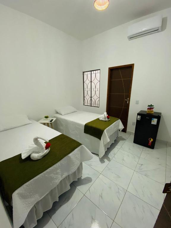 um quarto de hotel com duas camas e um cisne na cama em Pousada Bouganville da Serra em Serra de São Bento