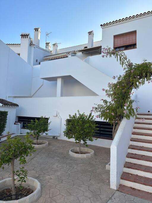 um edifício branco com escadas e árvores num pátio em Casa en las buganvillas Vera Playa em Playas de Vera
