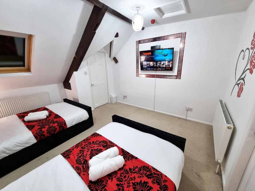 a bedroom with two beds and a tv on the wall at *RB1GH* For your most relaxed & Cosy stay + Free Parking + Free Fast WiFi * in Bramley