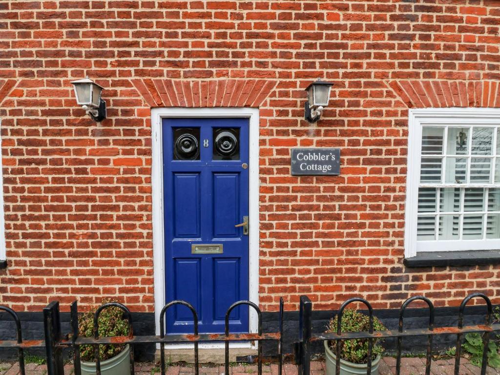 a blue door on the side of a brick building at Cobblers Cottage, Southwold in Southwold