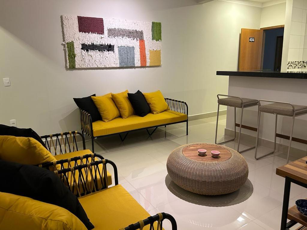 a living room with yellow couches and a table at Apartamento Luxo em Uberaba in Uberaba