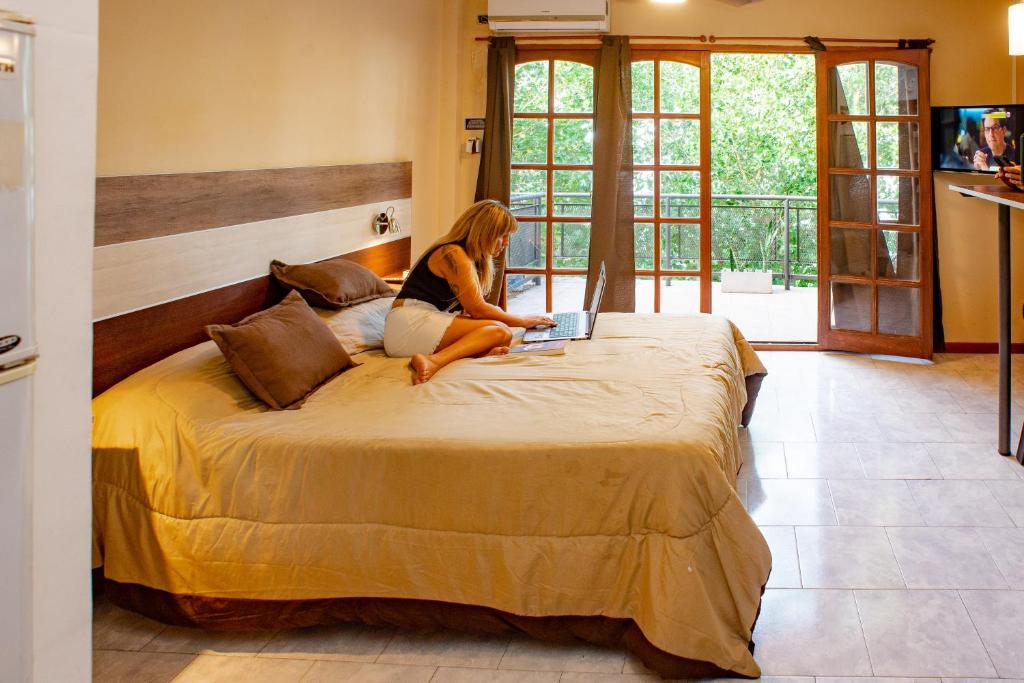 a woman sitting on a bed using a laptop at Altavista Aparts in Colón